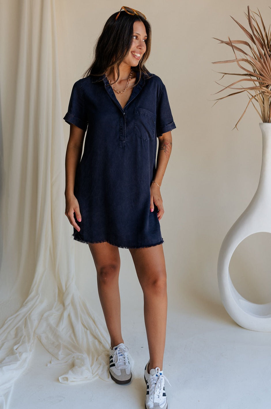 full boduy view of female model wearing the Leighton Navy Fray Short Sleeve Mini Dress which featuresNavy Blue Tencel Fabric, Fray Hem Details, Mini Length, Quarter Button-Up Closure, Collared Neckline, Short Sleeves and Left Front Chest Pocket