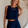 Upper body front view of female model wearing the Elara Navy Blue Tank Top that has a cropped waist and round neckline. worn with matching shorts.