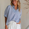Front view of female model wearing the Liora Striped Short Sleeve Button Up Top in blue that has blue and white stripes, a button up front, a collar, and short sleeves. Front tucked into white shorts.