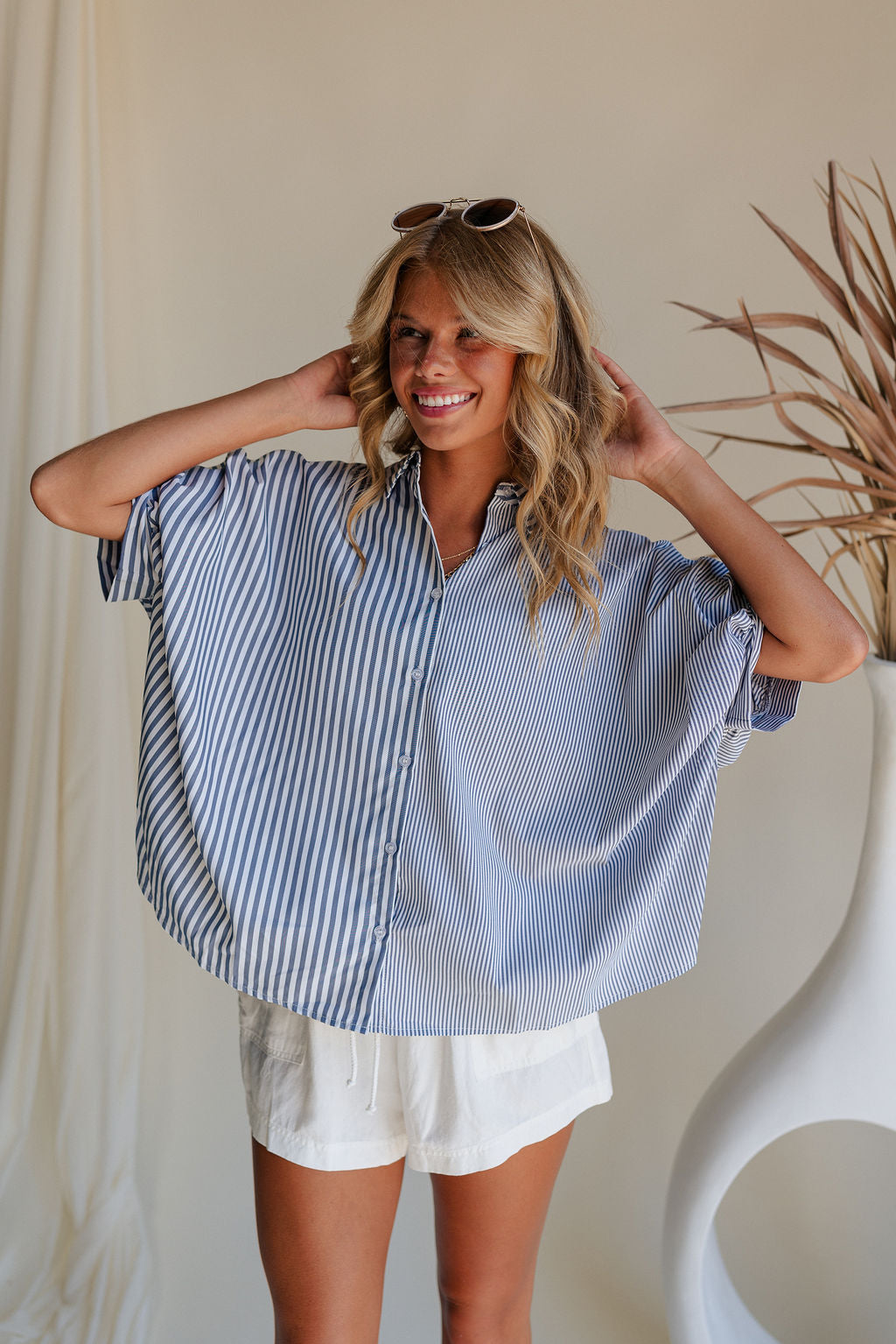 Front view of female model wearing the Liora Striped Short Sleeve Button Up Top in blue that has blue and white stripes, a button up front, a collar, and short sleeves.