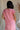 Upper body back view of female model wearing the Lumi Coral Short Sleeve Maxi Dress that has light coral fabric, short sleeves, and side pockets.