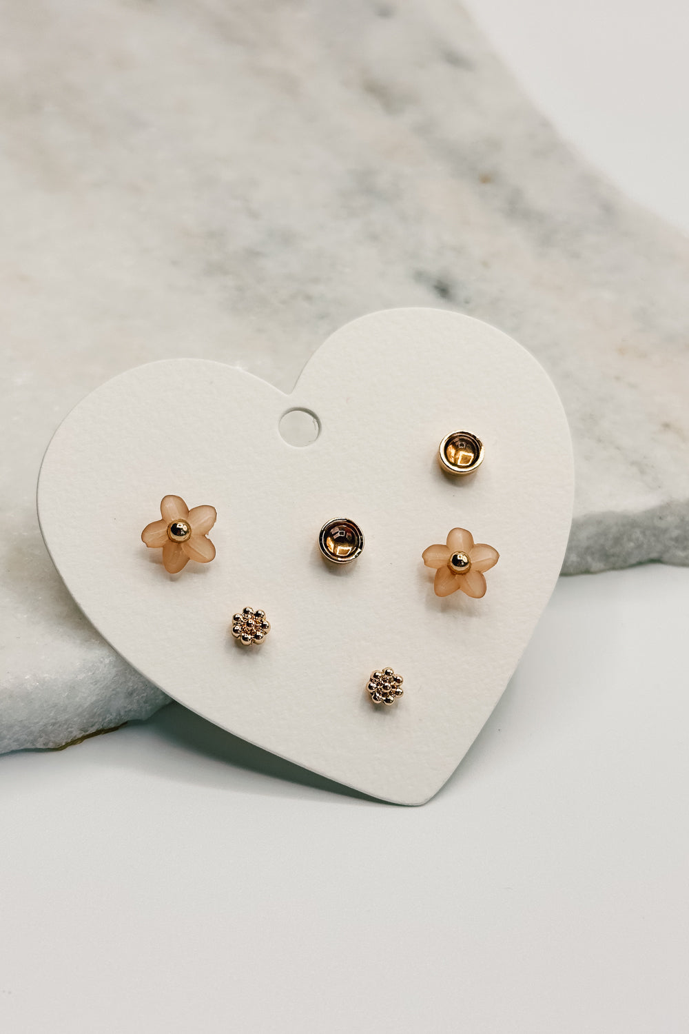 Close up view of the Eden Blush & Gold Stud Earring Set which features set of stud earrings include gold bead flowers, blush flower studs and amber gold studs