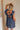 Back view of model wearing Savannah Navy Floral Mini Dress. This is a navy floral mini dress with ruffle upper details.