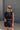 Close up view of model wearing Tatum Mini Skirt in black. This is a mini skirt with a drawstring waistband, bubble hem, and mini length.
