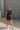 Full body view of model wearing Tatum Mini Skirt in black. This is a mini skirt with a drawstring waistband, bubble hem, and mini length.