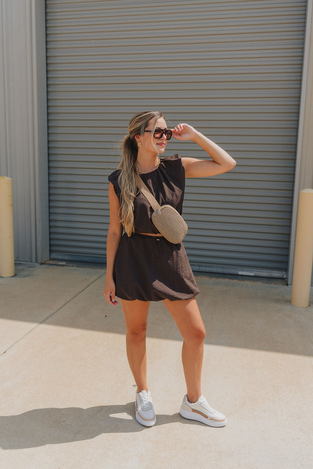 Full body view of model wearing Tatum Mini Skirt in espresso. This is a mini skirt with a drawstring waistband, bubble hem, and mini length.