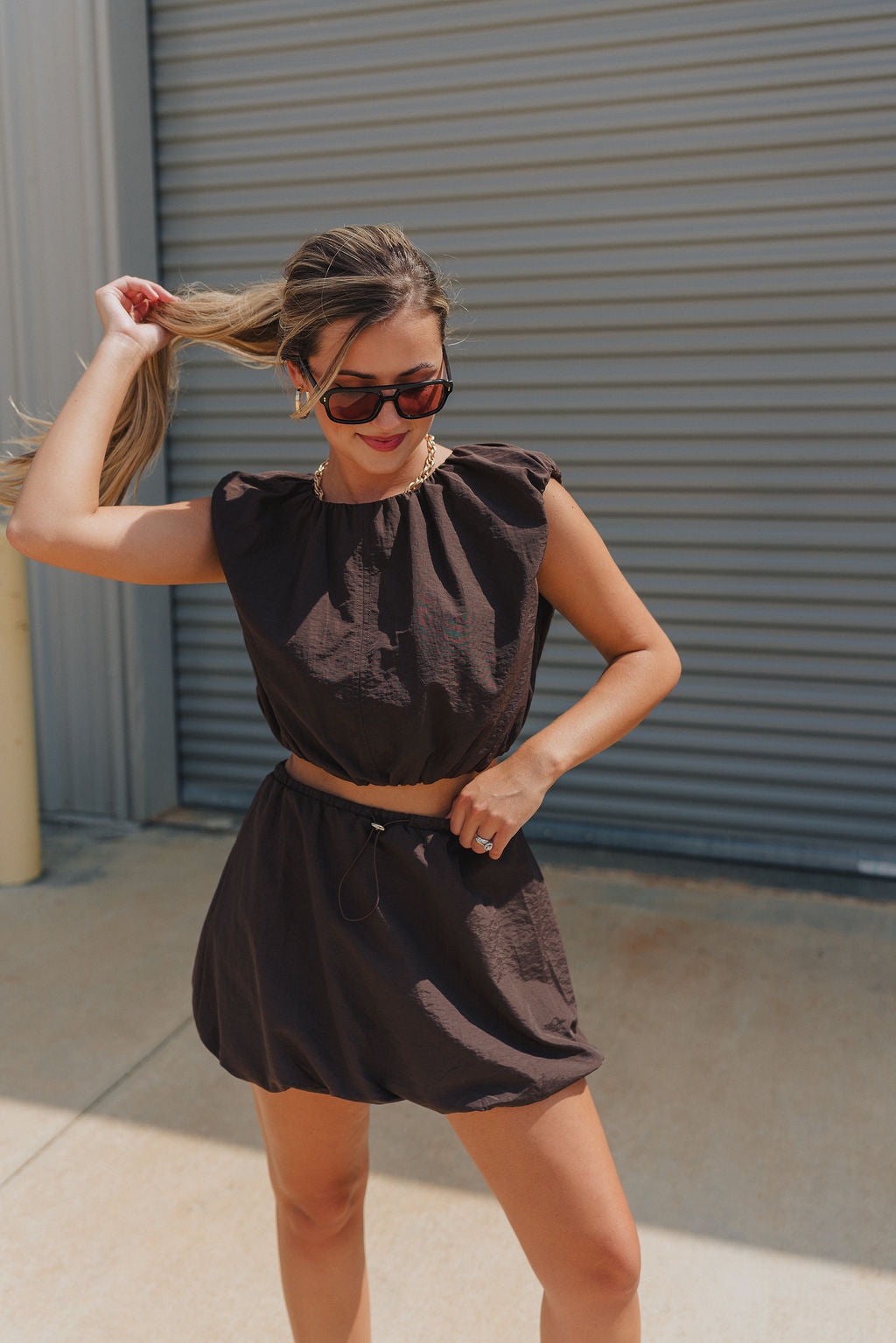 Full body view of model wearing Tatum Mini Skirt in espresso. This is a mini skirt with a drawstring waistband, bubble hem, and mini length.