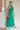 Side view of model wearing Madelyn Green Halter Maxi Dress. This is a green maxi dress with a halter criss cross neckline.