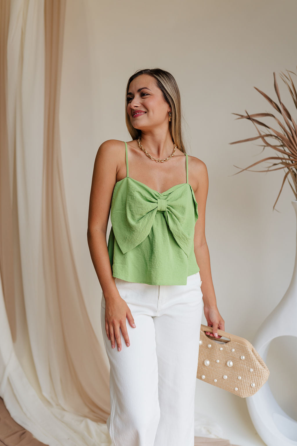 Close up of model wearing Kamryn Green Bow Tank. This is a light green tank with bow detail, sleeveless.