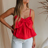 Close up of of model wearing Kendall Bow Tank in red. This is a peplum tank with bow detail coming in either red or maroon.