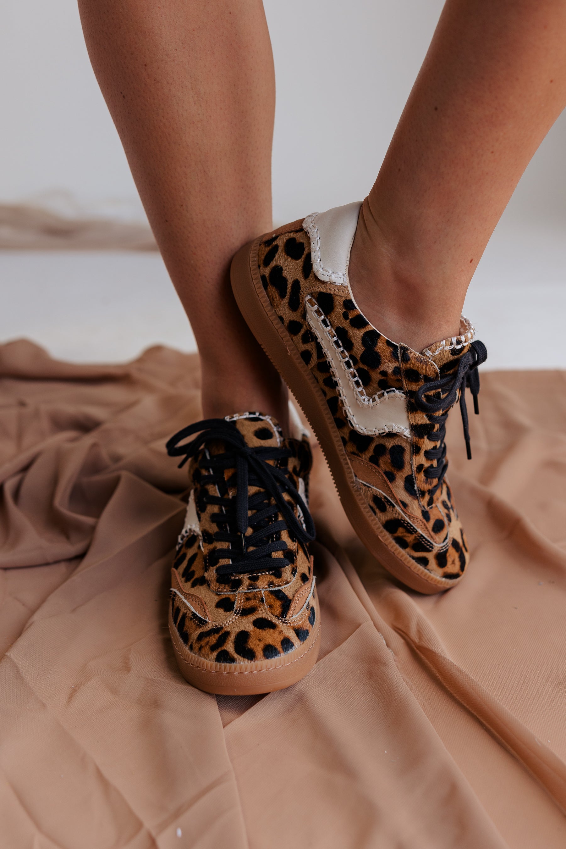 Image shows front and side view of model's legs- model is wearing the Notice Stitch Sneaker in Dark Leopard.