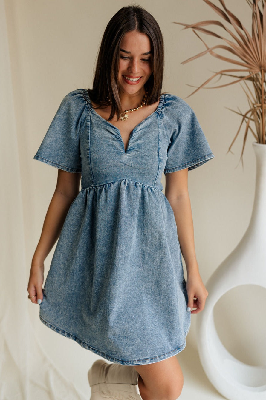front view of female model wearing the Charlie Light Denim V-Wire Mini Dress which features Denim Wash Fabric, Mini Length, Square Neckline with V Wire, Smocked Back and Short Puff Sleeves