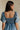 back view of female model wearing the Charlie Light Denim V-Wire Mini Dress which features Denim Wash Fabric, Mini Length, Square Neckline with V Wire, Smocked Back and Short Puff Sleeves