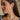 Side view of female model wearing the Vera Rhinestone & Gold Heart Shaped Huggie Earring which features heart shaped gold huggies with a clear stone detail
