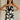 front view of female model wearing the Lila Black & Cream Tie Straps Romper which features Black and White Geometric Pattern, White Shorts Lining, Two Side Pockets, Ruffle Upper, Square Neckline and Tie Straps