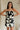 front view of female model wearing the Lila Black & Cream Tie Straps Romper which features Black and White Geometric Pattern, White Shorts Lining, Two Side Pockets, Ruffle Upper, Square Neckline and Tie Straps