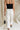 back view of female model wearing the Poppy White Buttoned Wide Leg Pants which features White Lightweight Fabric, Cropped Wide Leg, Front Zipper with Button Closure, Two Front Pockets with Monochrome Buttons and Two Back Pockets