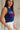 Upper body side view of female model wearing the USA Navy Knit Flag Tank Top that has navy knit fabric, a stitched flag with red stripes and white USA text, and a round neck.