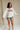 Full body front view of female model wearing the USA Ivory Graphic Sweatshirt that has ivory fabric, USA written in red letters, long sleeves, and a round neck.