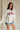 Upper body front view of female model wearing the USA Ivory Graphic Sweatshirt that has ivory fabric, USA written in red letters, long sleeves, and a round neck.