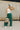Full body view of model wearing the Emerson Pants in green. These are comfy pants with a ruched waistband, cargo pant look, comes in either black or green.