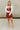 Full body front view of female model wearing the Anya Burgundy Faux-Leather Strapless Dress that has burgundy faux-leather fabric, a strapless neck, and mini-length hem. Worn under a beige cropped cardigan.