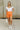 Full body front view of female model wearing the Stacey Orange Denim Pearl Shorts paired with a white bodysuit.