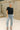 Full body view of model wearing the Millie Crochet Short Sleeve Sweater in black. This is a cropped sweater top, crochet, short sleeve, comes in either black, white, or khaki.