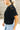 Close up side view of model wearing the Millie Crochet Short Sleeve Sweater in black. This is a cropped sweater top, crochet, short sleeve, comes in either black, white, or khaki.