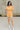 Full body view of model wearing the Tatum Orange and Cream Checkered Romper. This is an orange and cream checkered romper, with short sleeves, button up front, and a collared neckline.