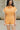 Close up view of model wearing the Tatum Orange and Cream Checkered Romper. This is an orange and cream checkered romper, with short sleeves, button up front, and a collared neckline.
