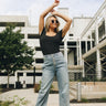 Full body view of model wearing the Lilly Blue Jeans. These are blue denim jeans with multiple button closure, pockets on back.