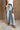 Lower body front view of female model wearing the Greer Wide Legs Jeans that have light wash denim, frayed hems, and a front zipper and button closure