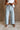 Lower body front view of female model wearing the Greer Wide Legs Jeans that have light wash denim, frayed hems, and a front zipper and button closure
