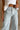Close-up front view of female model wearing the Greer Wide Legs Jeans that have light wash denim, frayed hems, and a front zipper and button closure