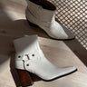 Side and top view of the Jackson White Ankle Boots that have white uppers, brown block heels, inner zipper, and outer strap details.