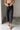 Lower body front view of female model wearing the Rosalind Black Barrel Jeans with a brown tank top and black heels.