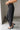 Lower body side view of female model wearing the Rosalind Black Barrel Jeans with a brown tank top and black heels.