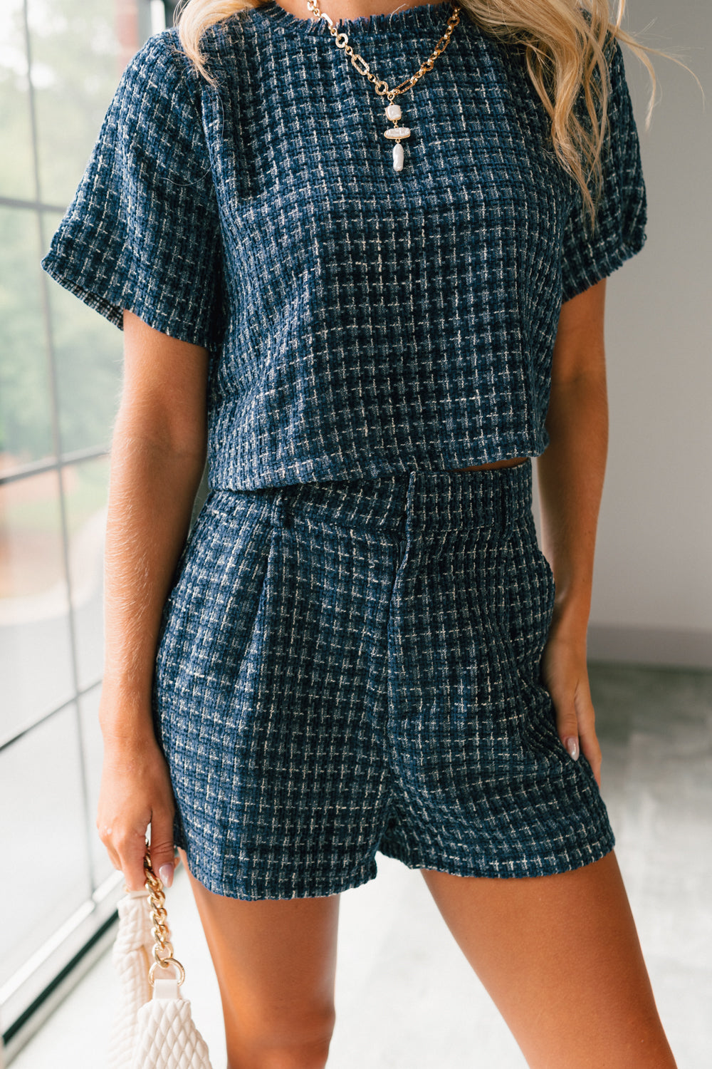 Front view of female model wearing the Jemma Navy Tweed Shorts that have navy and white tweed and side pockets. Worn with matching top.