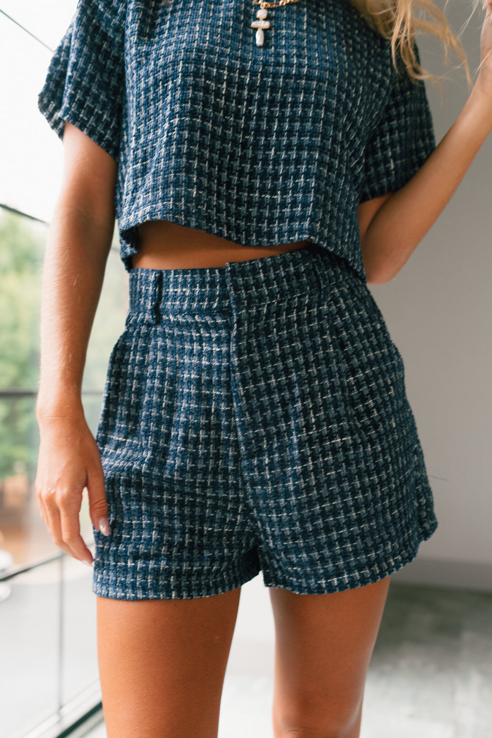 Front view of female model wearing the Jemma Navy Tweed Shorts that have navy and white tweed and side pockets. Worn with matching top.