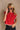 Upper body front view of female model wearing the Baleigh Red Knit Top that has red knit fabric with white trim.