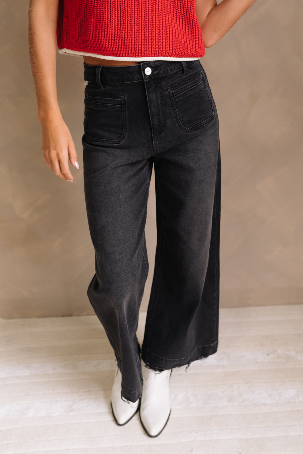 Lower body front view of female model wearing the Ceros: Florence Black Wide Leg Jeans with a red top.