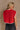 Back view of female model wearing the Baleigh Red Knit Top that has red knit fabric with white trim.