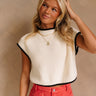 Close up of model wearing the Marleigh Cream Knit Top. This is a cream knit cropped top, sleeveless, with black trimming.