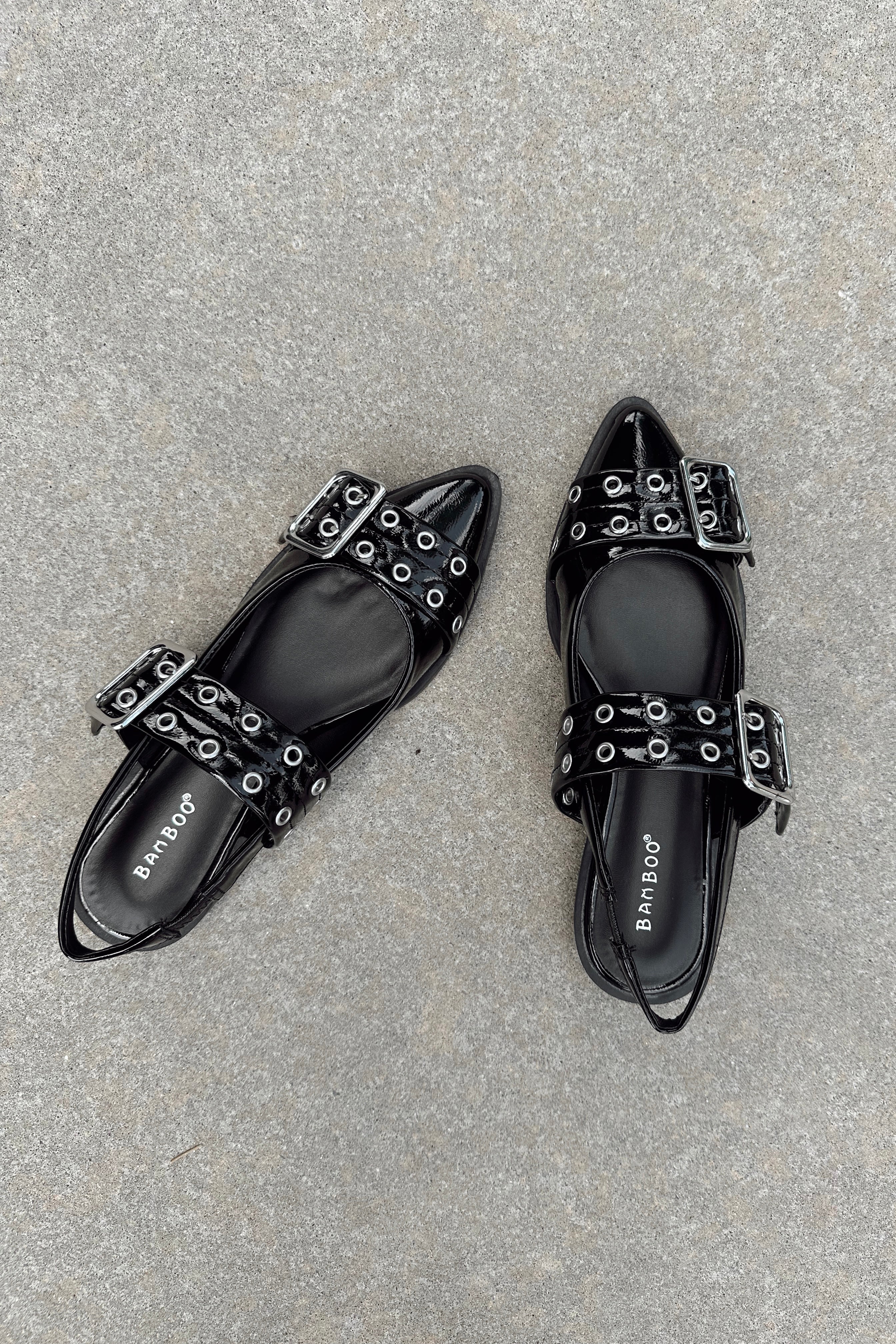 Top view of the Livia Black Patent Buckle Flats that have black patent material, pointed toles, and silver buckle details.