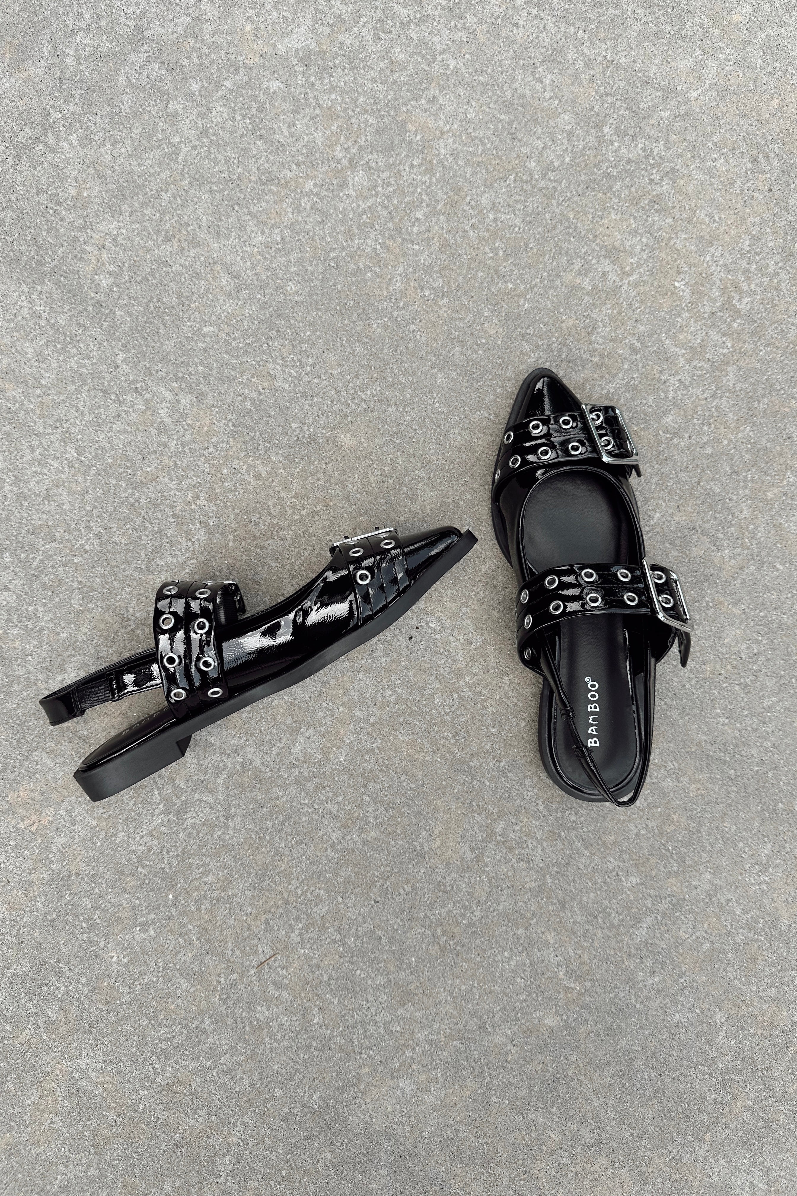 Top and side view of the Livia Black Patent Buckle Flats that have black patent material, pointed toles, and silver buckle details.