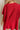 Back view of female model wearing the Heather Oversized Sweater in Red, which has a round neck, side slits, and short poncho sleeves. 