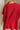 Back view of female model wearing the Heather Oversized Sweater in Red, which has a round neck, side slits, and short poncho sleeves. 