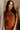 Close upper front view of female model wearing the Monica Rust Mock Neck Sweater Dress that has rust colored knit fabric, a mock neck, and mini length hem.