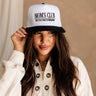 Front view of female model wearing the Mom's Club Trucker that is white with a black bill and text. Text on front says "MOM'S CLUB EST. TOO TIRED TO REMEMBER" and the back says "The happiest :)"